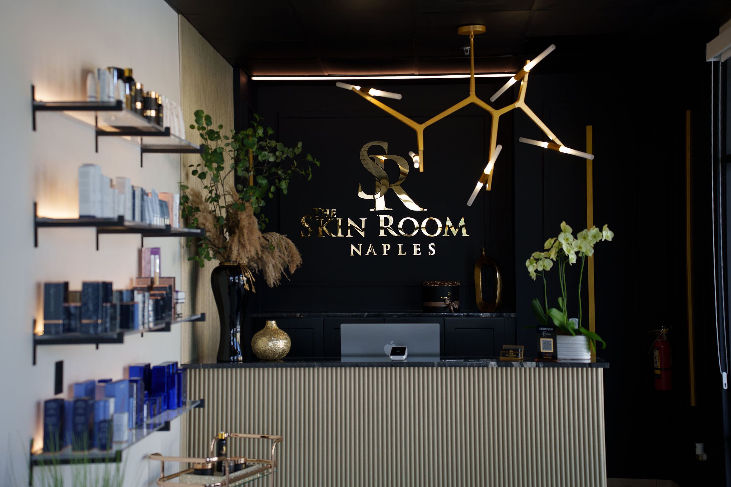 The front desk of The Skin Room, with the gold logo wall behind it