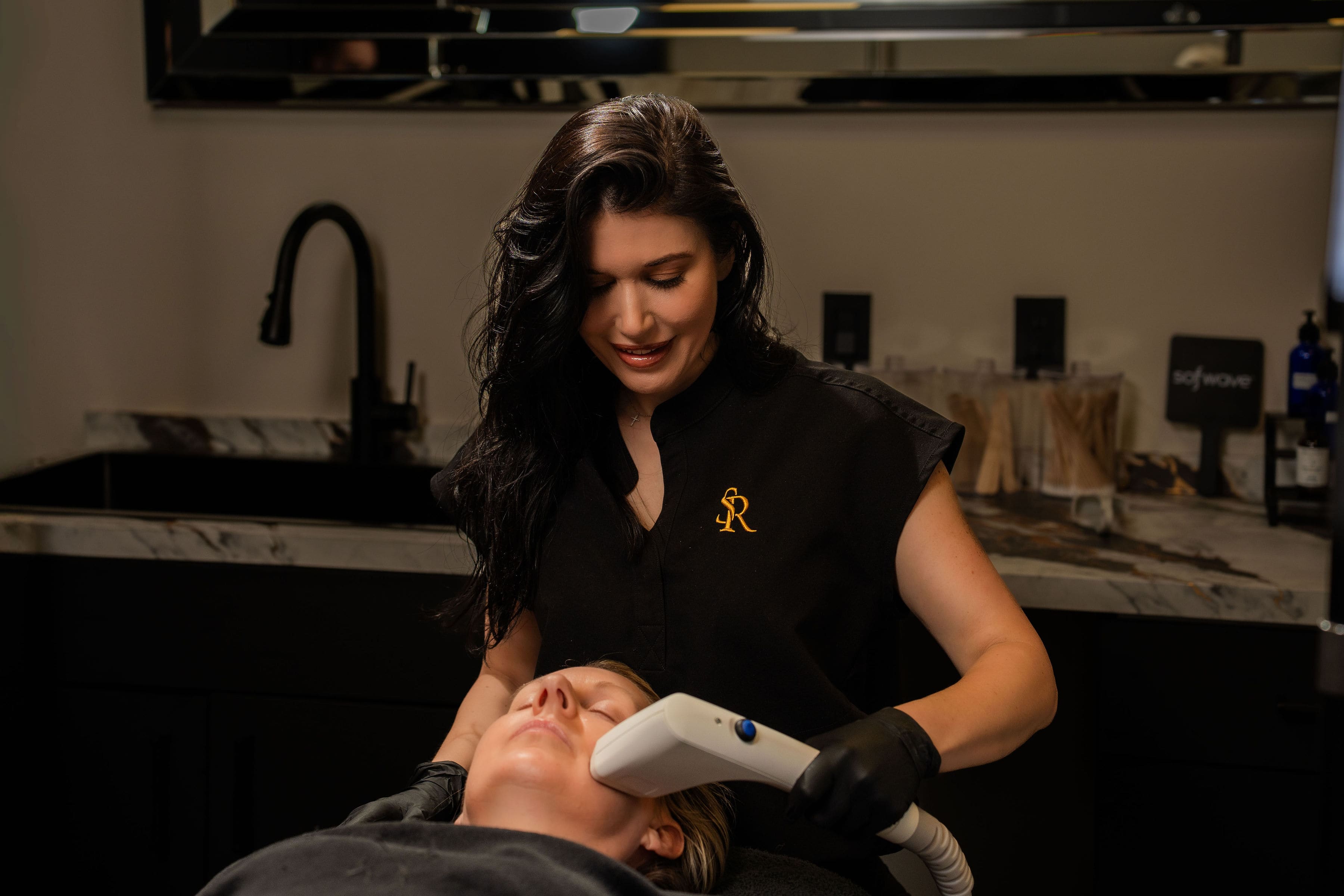 Erica Current giving a client a Sofwave treatment, the Sofwave sign behind her