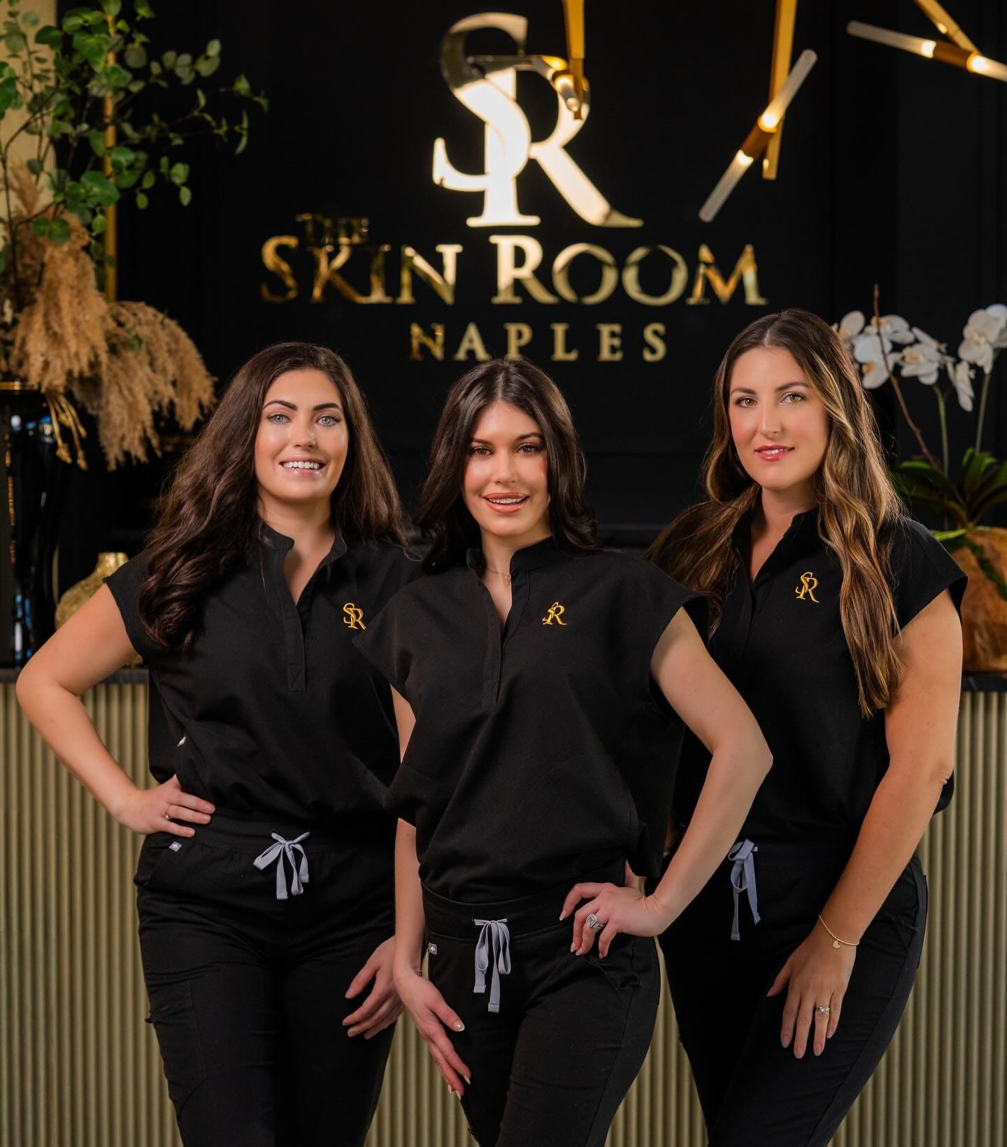 Jayna Baggs, Erica Current and Rachel Coapman at the front desk, under The Skin Room logo