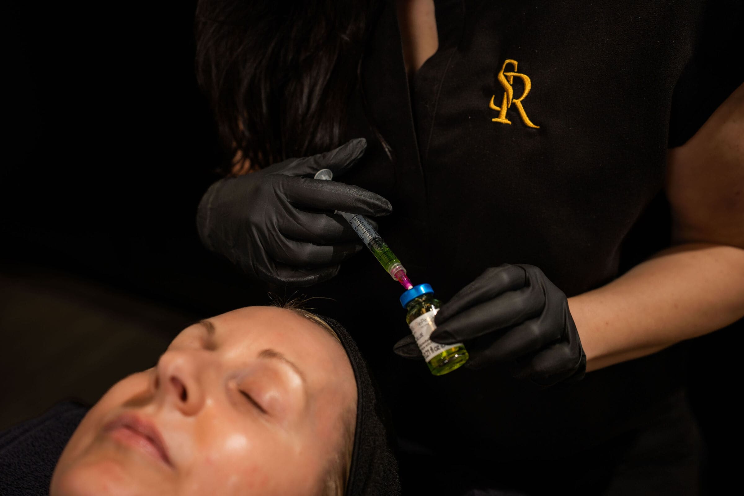 A provider drawing a peel from its vial beside a client's face